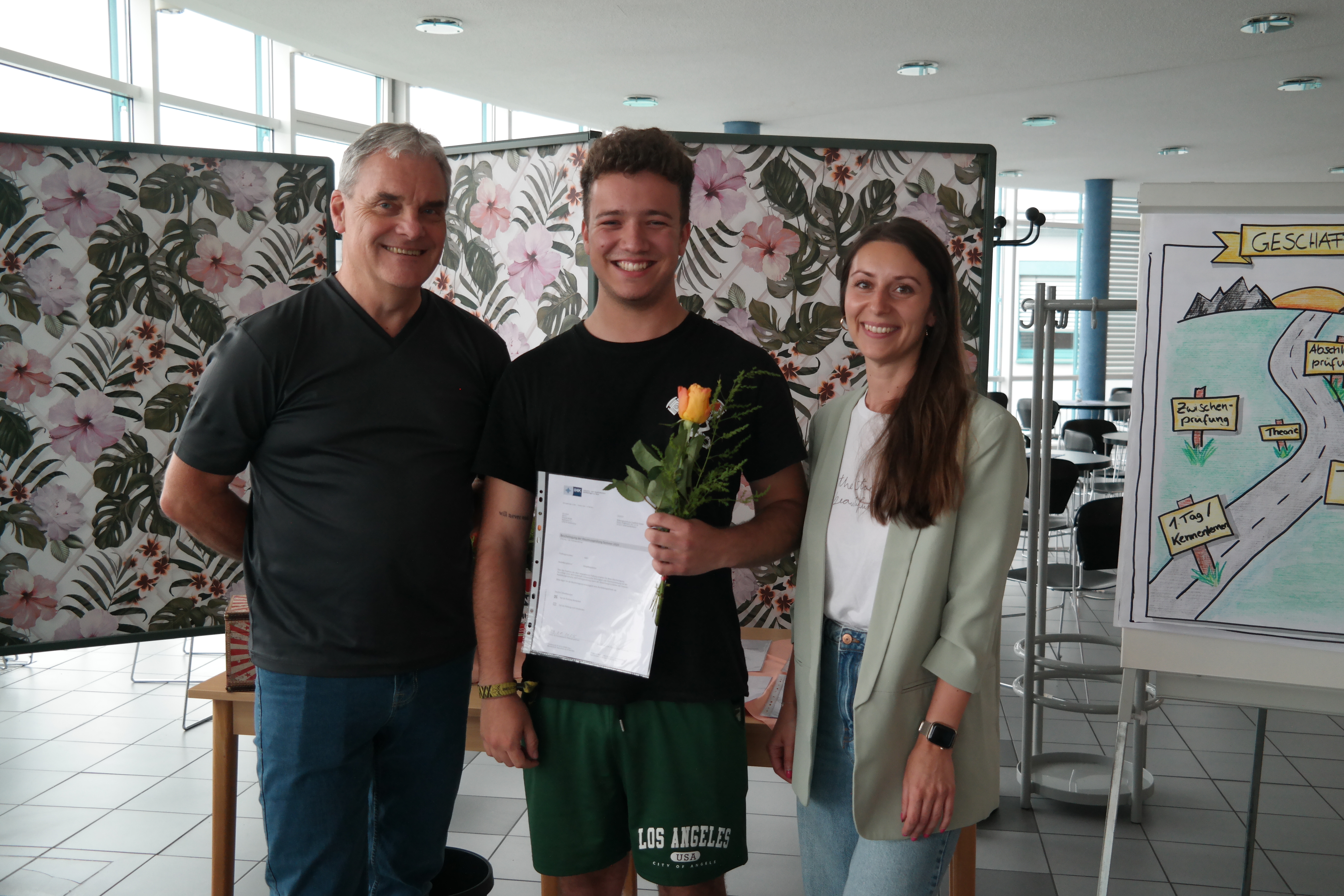 zwei Ausbilder und ein Azubi mit Zeugnis